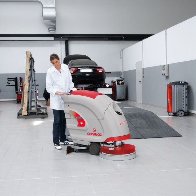 Person operating a floor cleaning machine in a garage setting