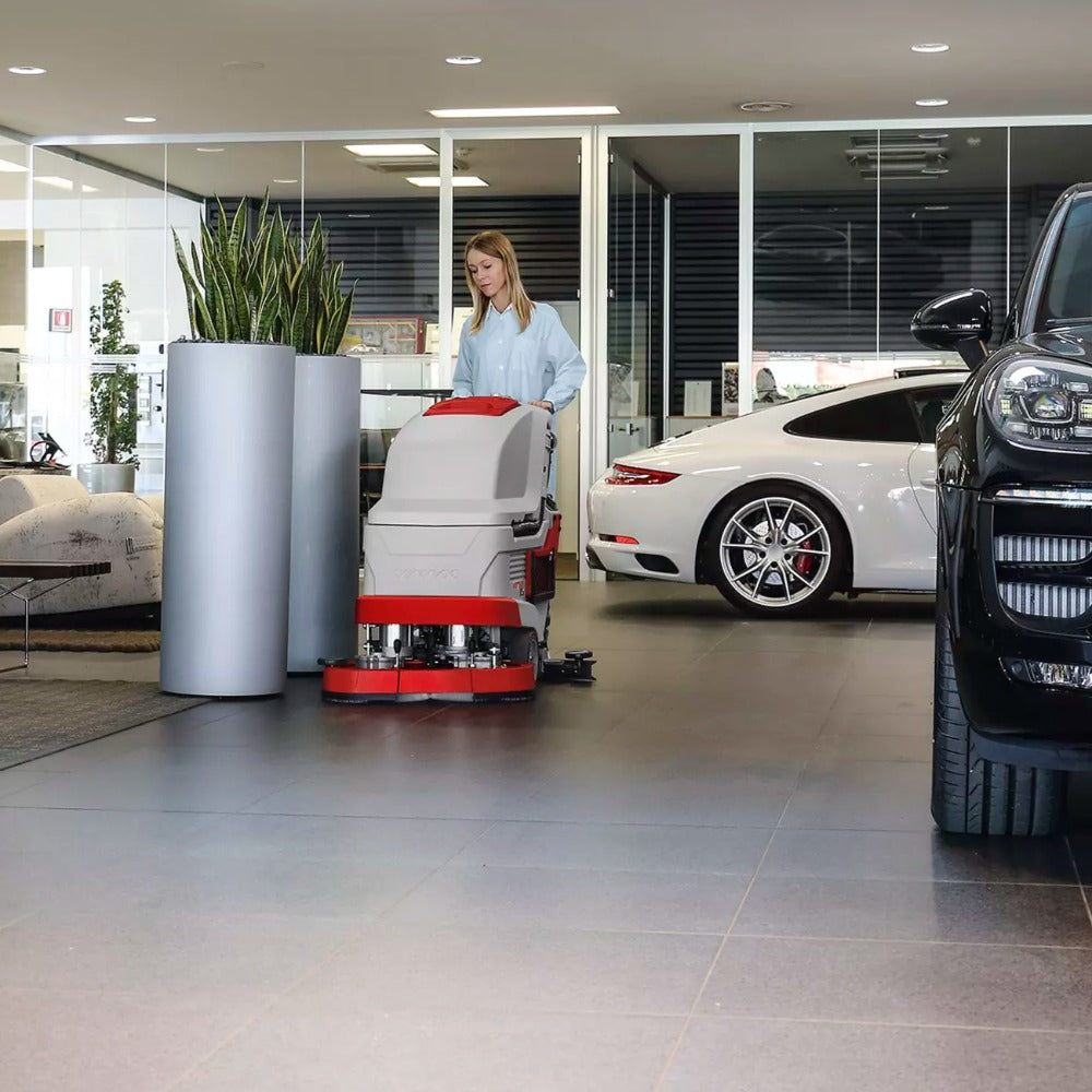 Person operating a floor cleaning machine in a car showroom