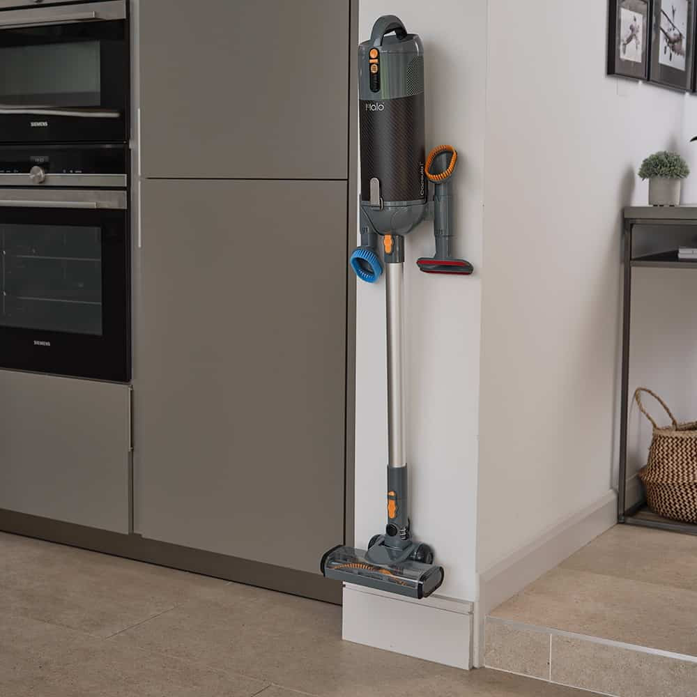 Halo Capsule Stick Vacuum Cleaner with attachments against a kitchen wall