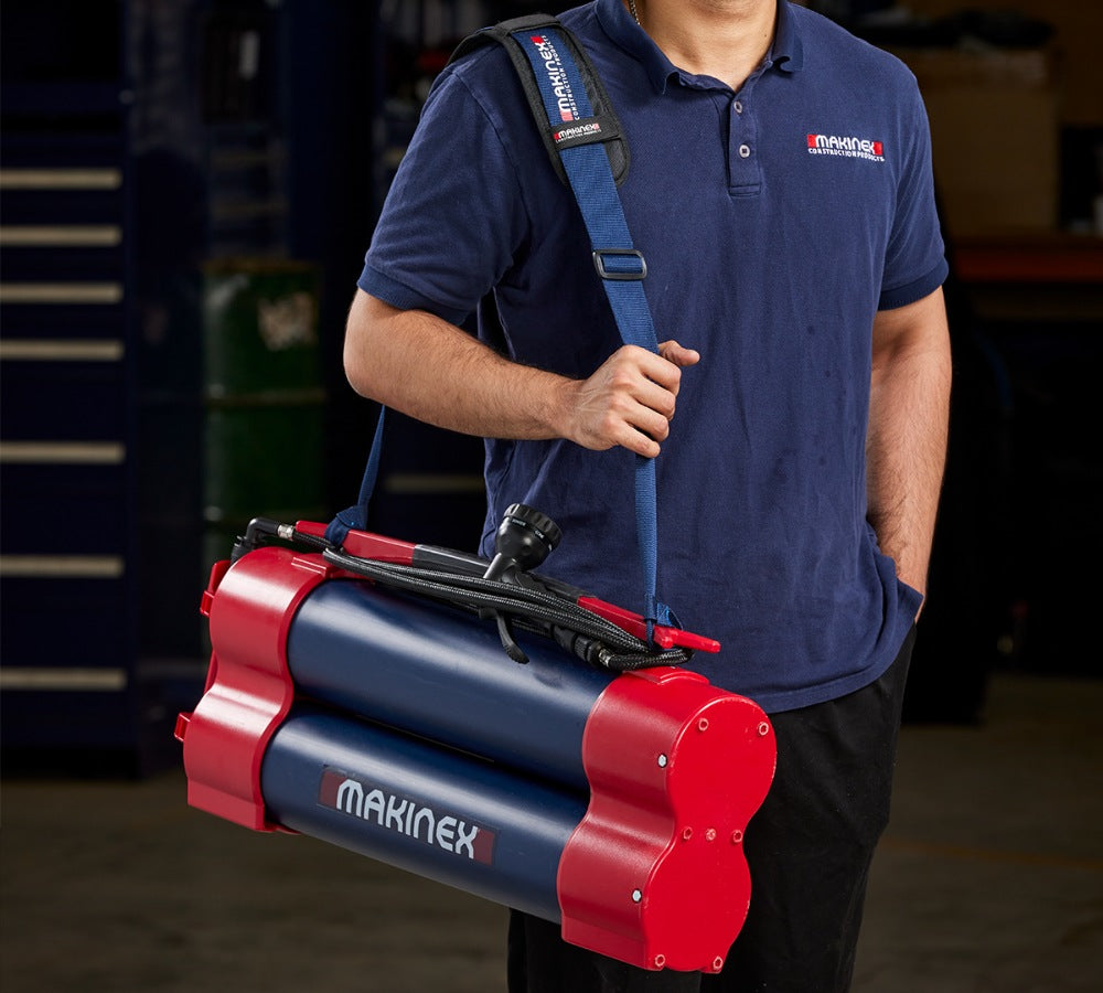 Person carrying a red and blue Makinex Hose 2 Go Water Supply in a workshop setting.