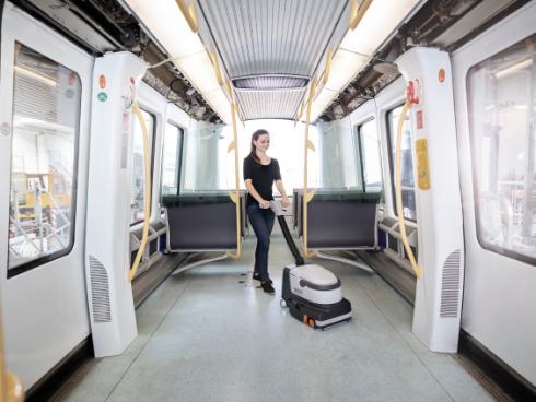 Person cleaning inside a modern train with a Nilfisk SC250 Scrubber cleaning machine.
