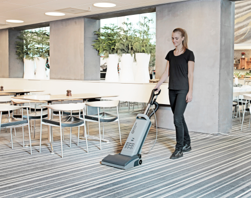 Person using a Nilfisk VU500 Upright Vacuum Cleaner 15" in a restaurant setting