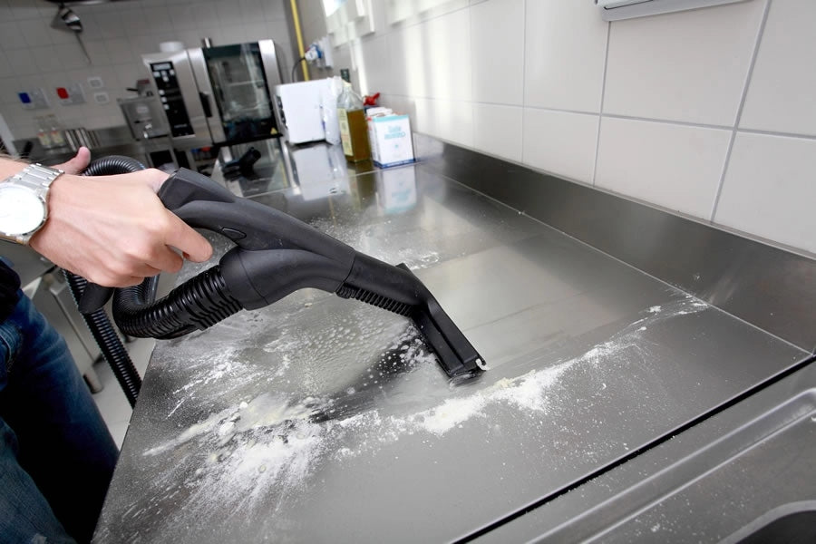 Person using a Novaltec Black Hawk Virucide on a kitchen countertop with flour scattered.