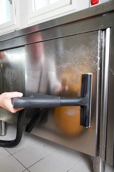 Person using a Novaltec Black Hawk Virucide to clean a stainless steel appliance.