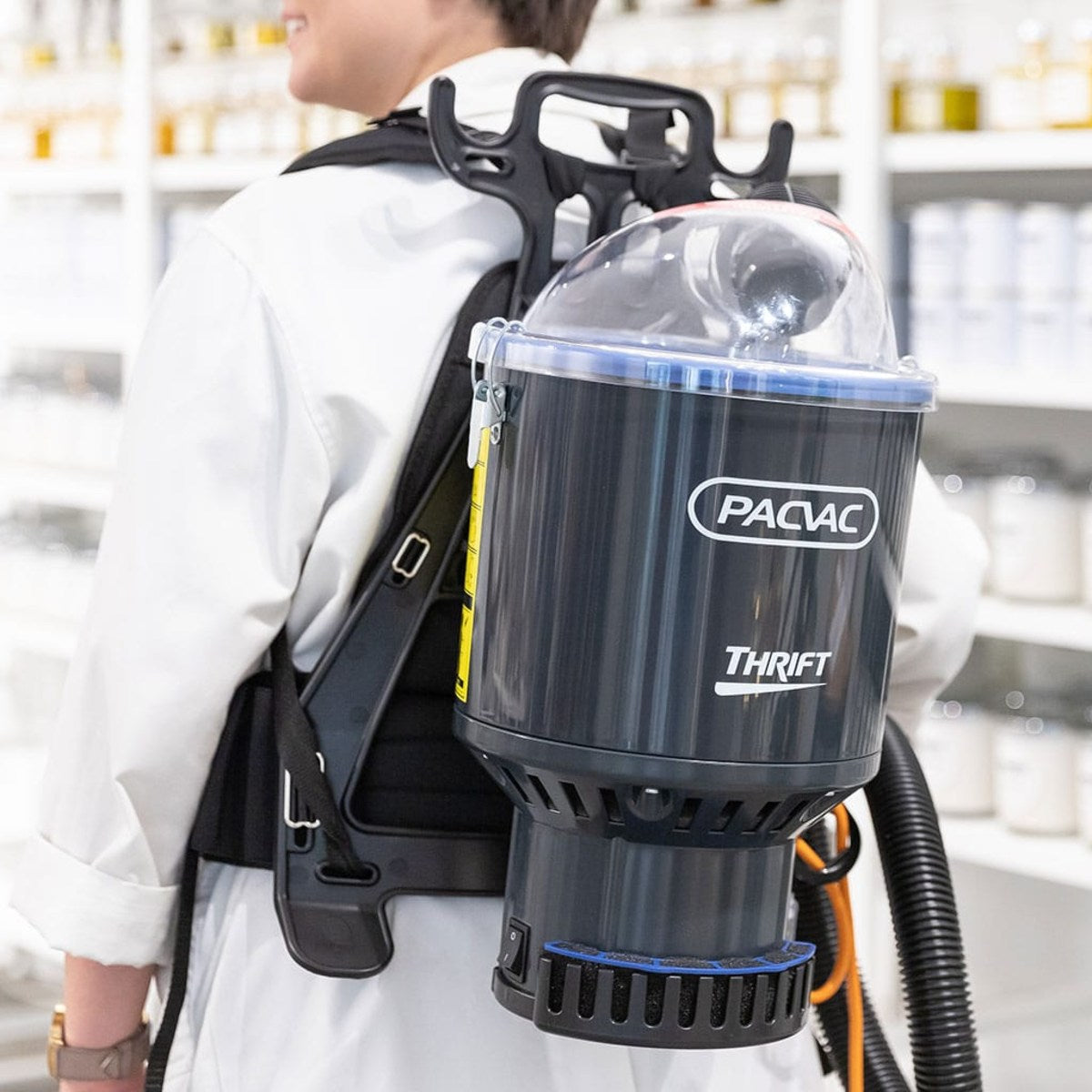 Person wearing a backpack with a Pacvac Thrift vacuum cleaner in a laboratory setting