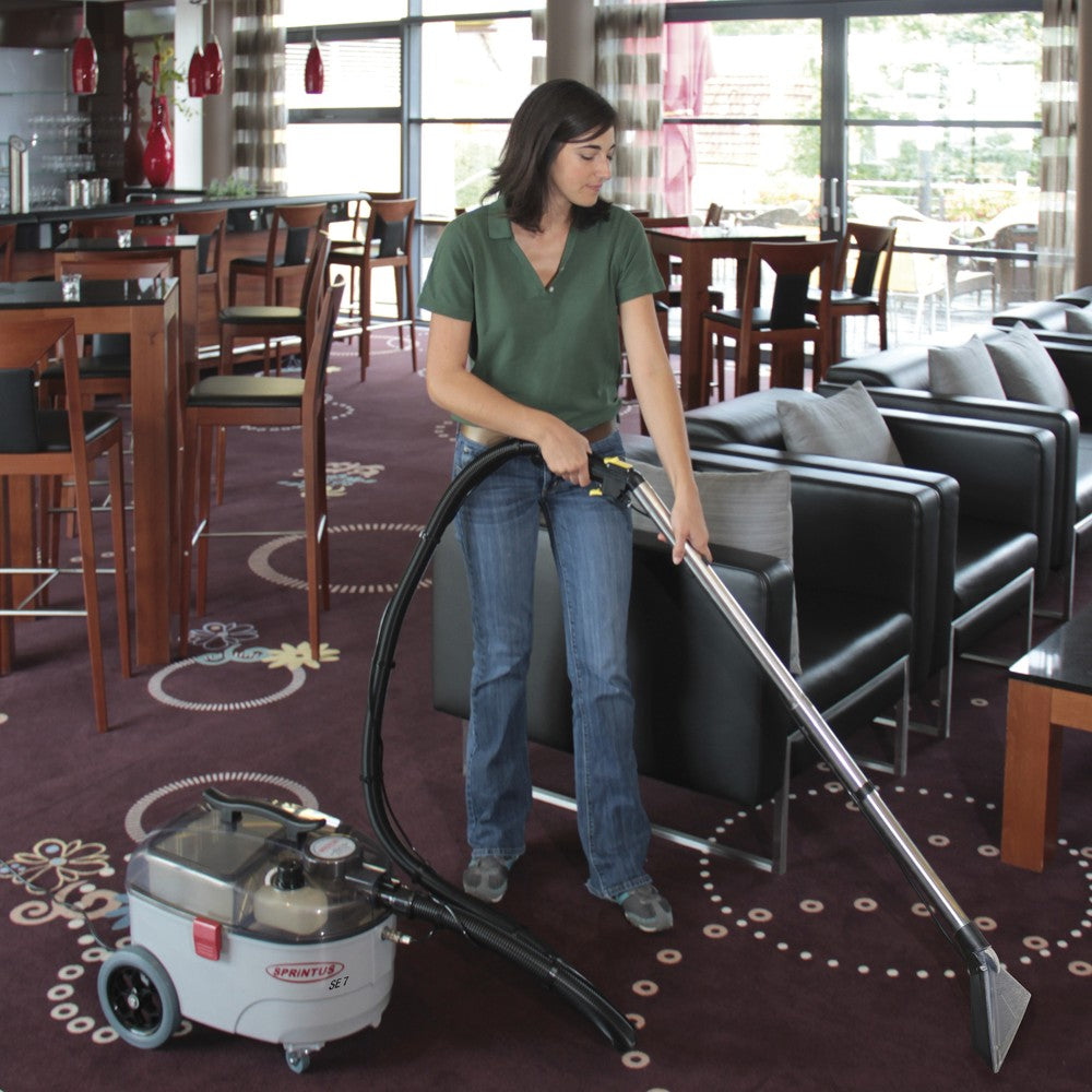 Person using a carpet cleaning machine in a restaurant setting