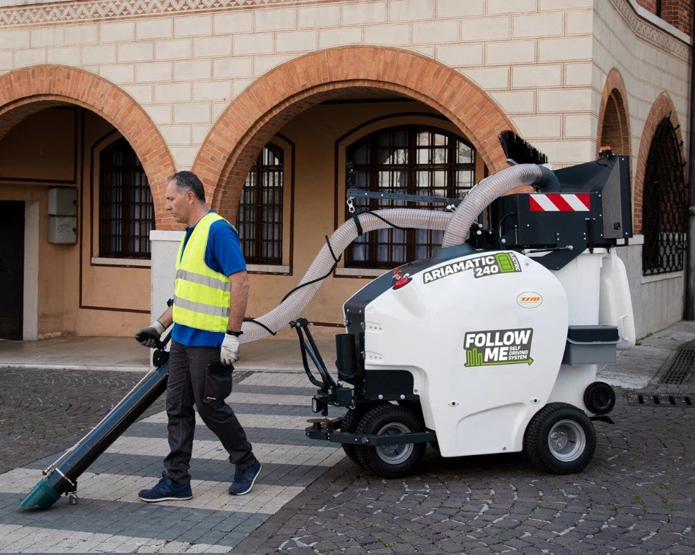 Person operating a TSM Ariamatic 240 on a street with a building in the background