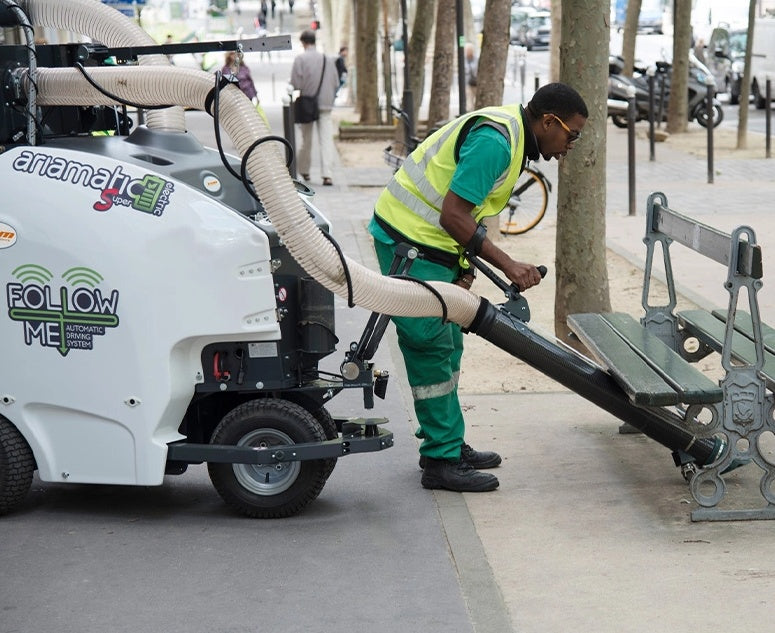 Person in green uniform using a TSM Ariamatic 240 on a sidewalk