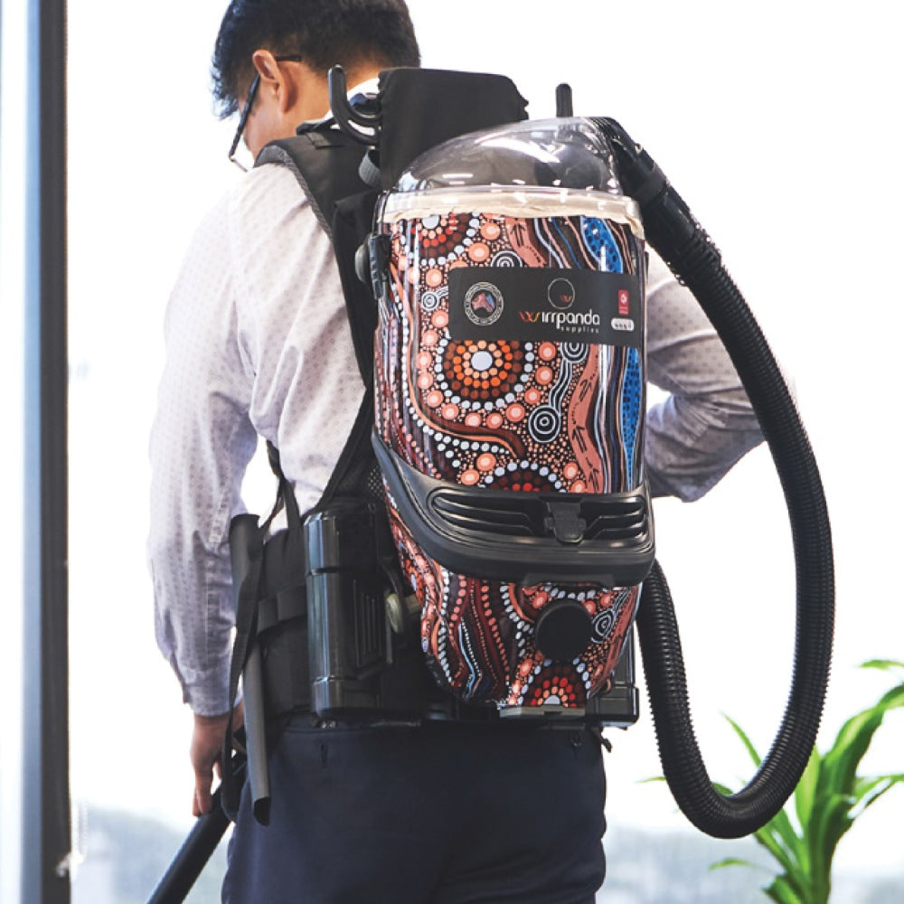 Person wearing a backpack with a colorful design, holding a hose, with a blurred background.
