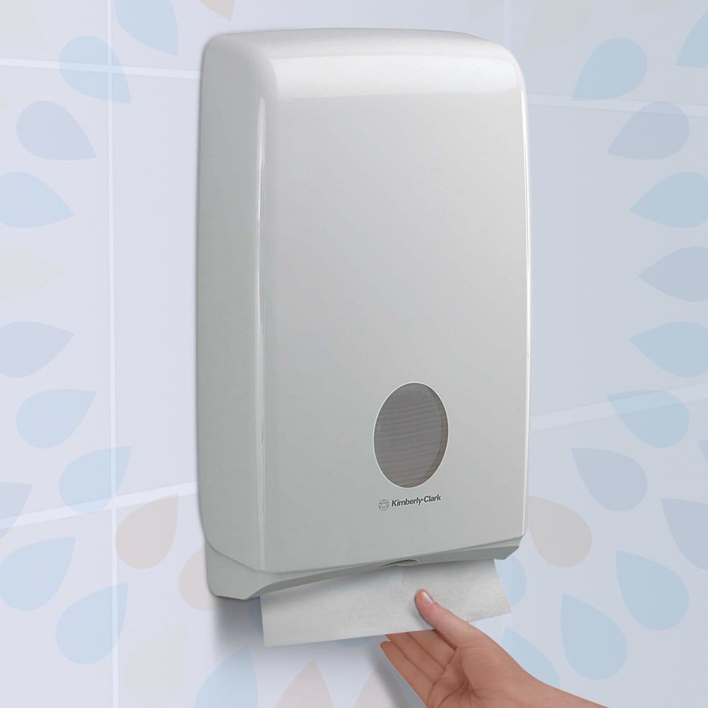 Hand using a Kimberly-Clark paper towel dispenser against a light blue tiled wall.
