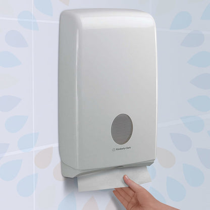 Hand using a Kimberly-Clark paper towel dispenser against a light blue tiled wall.