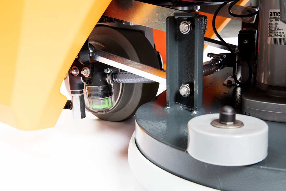 Close-up of a scrubbing machine with wheels and mechanical components on a white background