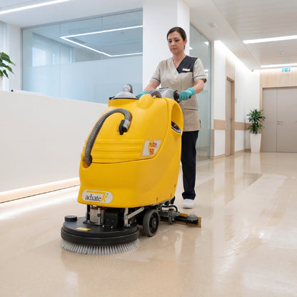 Person operating a yellow floor cleaning machine in a medical healthcare setting
