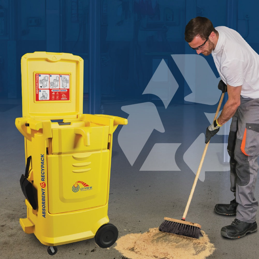 Person using a broom to clean up a spill next to a yellow hazardous material cleanup kit.