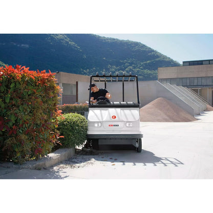 Person driving a Comac CS120B Ride On Sweeper on a sunny day with mountains in the background