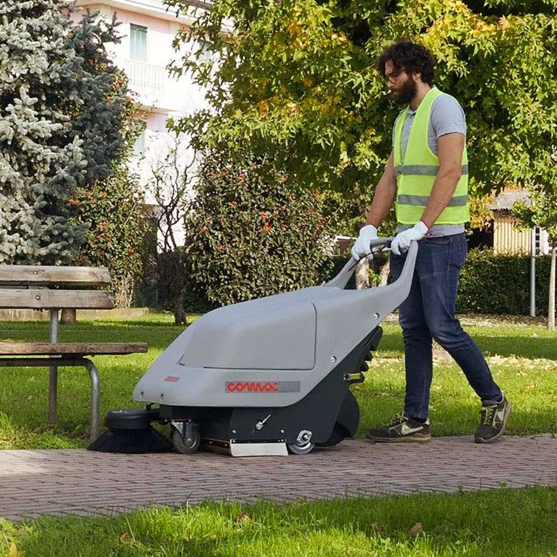 Person using a Comac CS50 on a sidewalk with grass and trees in the background
