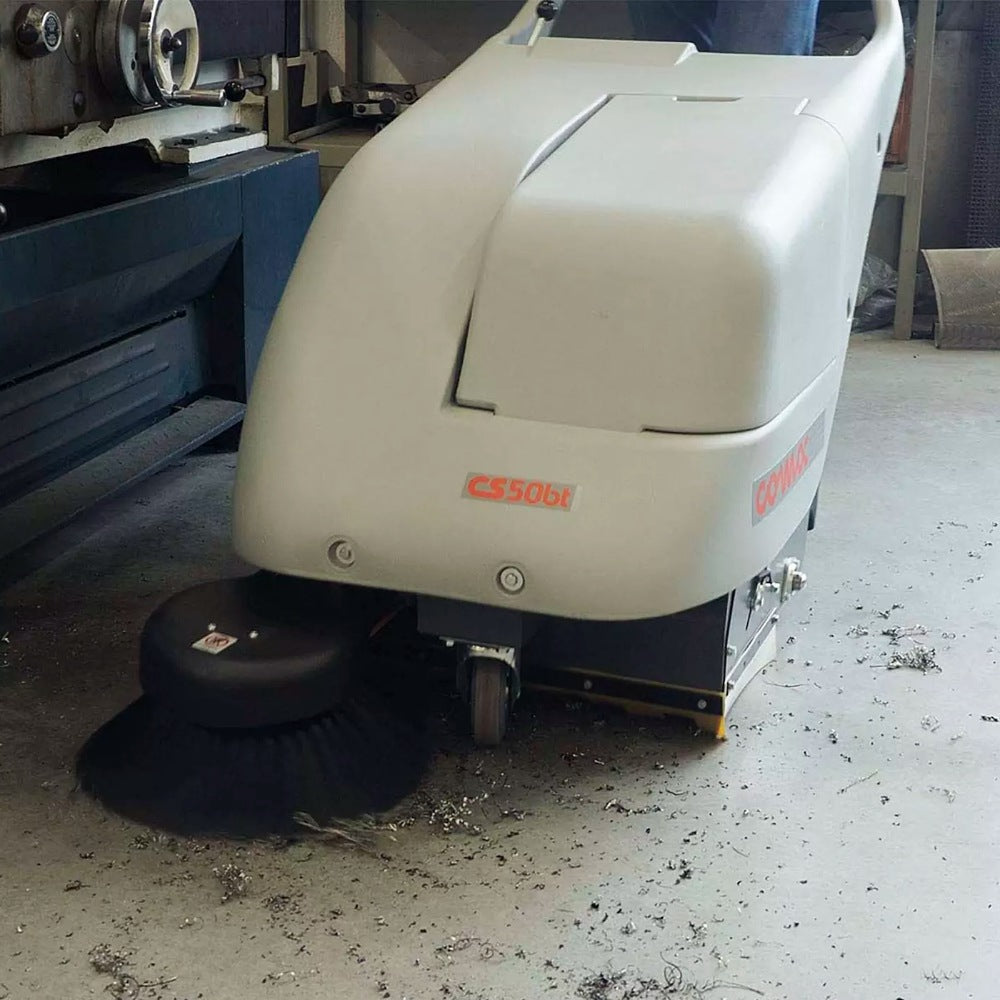 Floor cleaning machine on a dirty floor with a workshop background