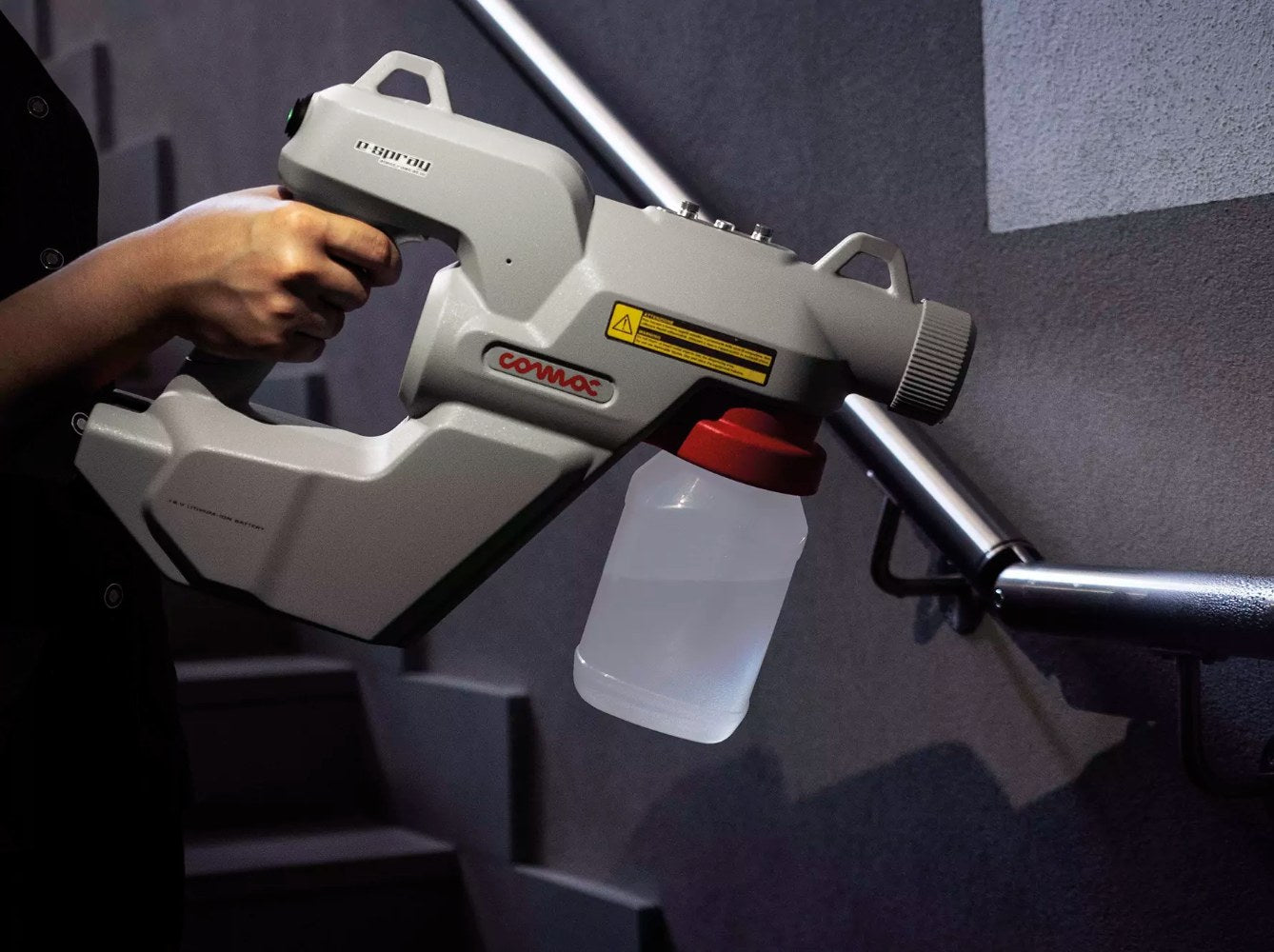 Person holding a Comac Electrostatic E-Spray on a dark background
