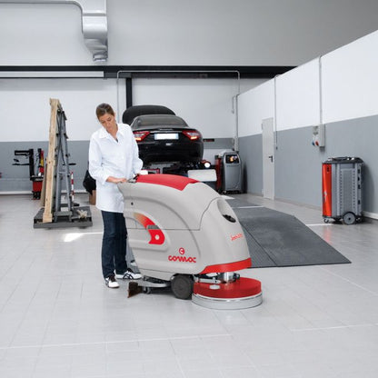 Person operating a floor cleaning machine in a garage setting