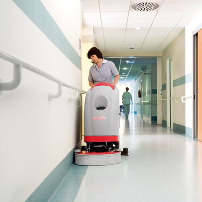Person operating a floor cleaning robot in a hospital hallway