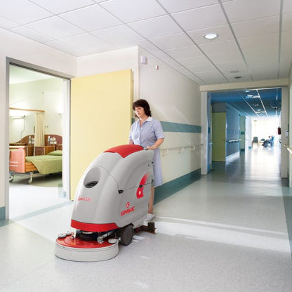 Person operating a floor cleaning machine in a hospital corridor