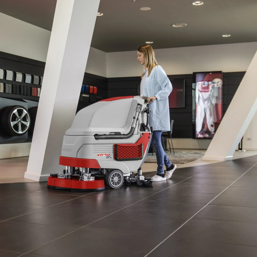 Person pushing a floor cleaning machine in a showroom setting