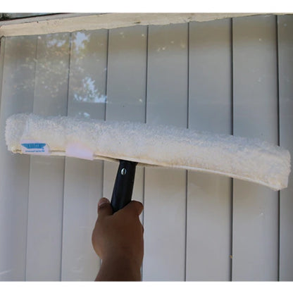 Person using a squeegee to clean a window with a gray wall in the background