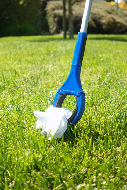 Blue and white reaching tool in grass