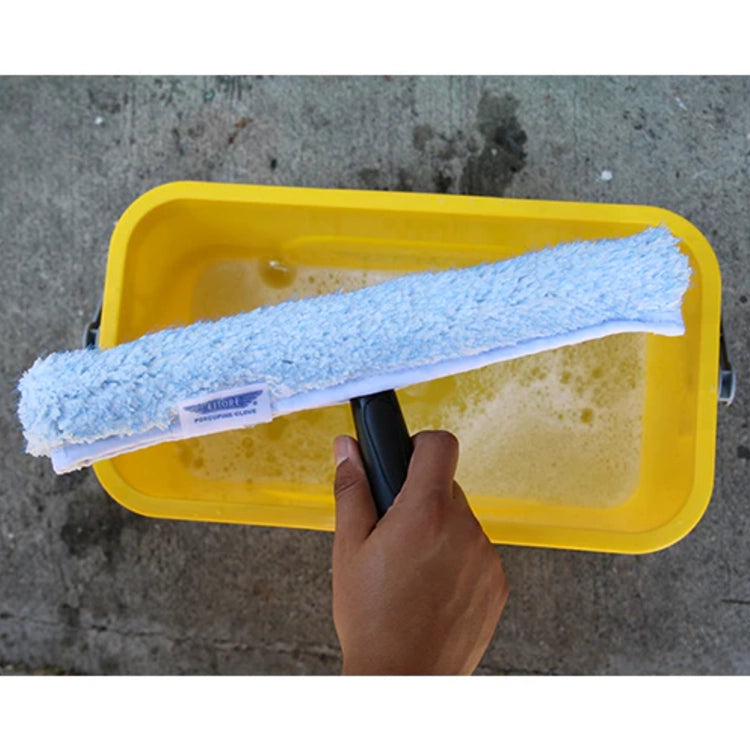 Person holding a yellow bucket with a blue cleaning pad inside on a concrete surface