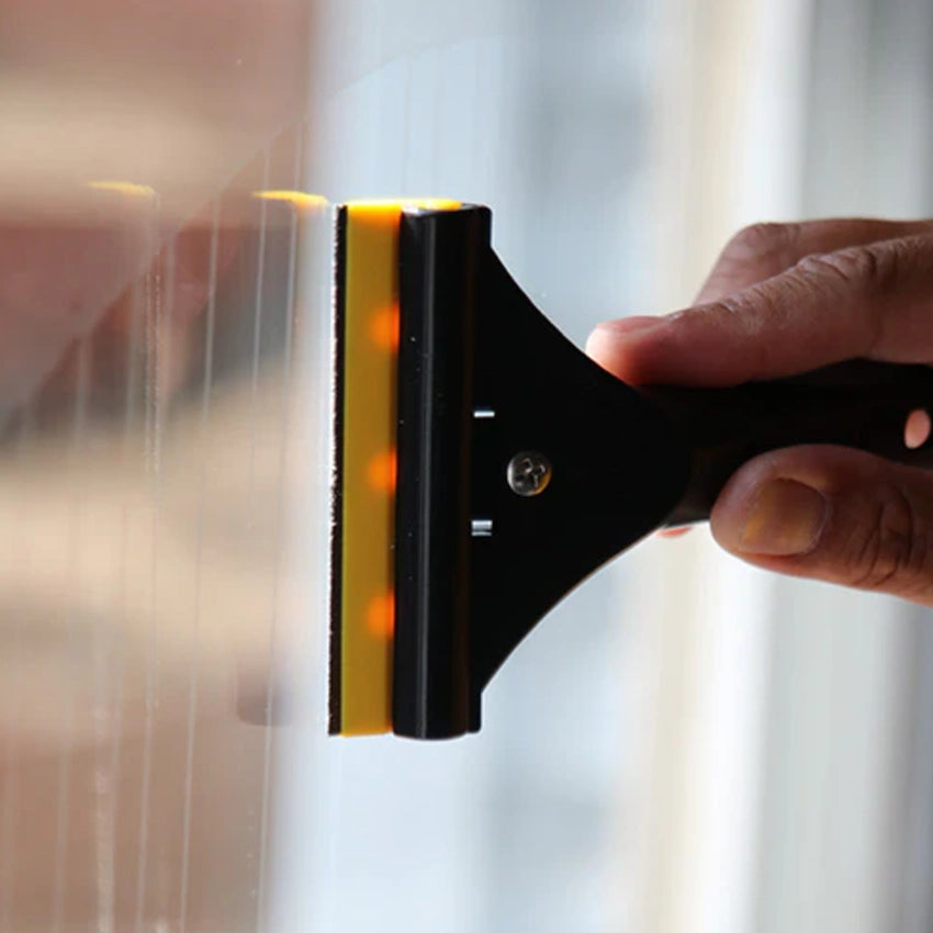 Person using a squeegee to clean a window with a blurred background