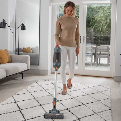 Woman using a Halo Capsule Stick Vacuum Cleaner on a rug in a living room.