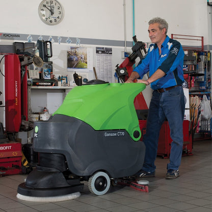 Man operating a green and black IPC CT70 ECS Auto Scrubber in a workshop setting.