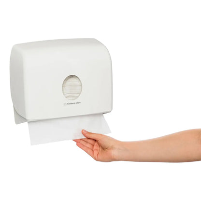 White paper towel dispenser with a hand pulling out a sheet of paper towels.