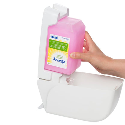 Hand holding a Kleenex pink soap container installing into dispenser