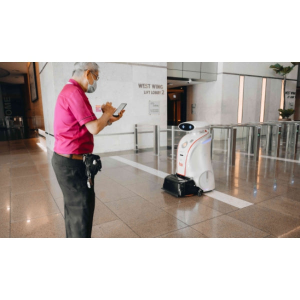 Person using a smartphone to control a Lionsbot Leobot Vacuum robot cleaner in a building lobby