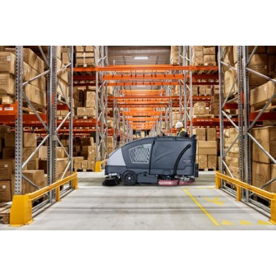 Floor cleaning machine in a warehouse setting with pallets and boxes