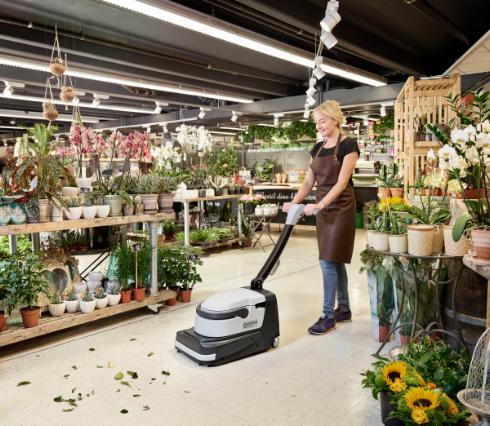 Person using a Nilfisk SC250 Scrubber floor cleaning machine in a flower shop.