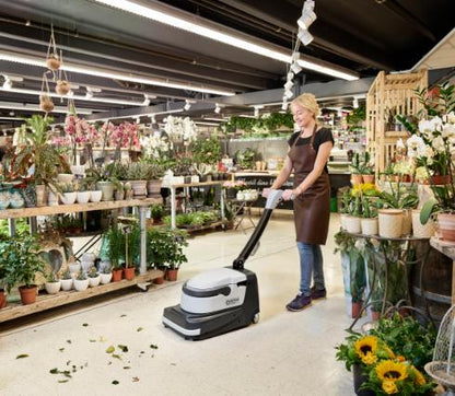 Person using a Nilfisk SC250 Scrubber floor cleaning machine in a flower shop.