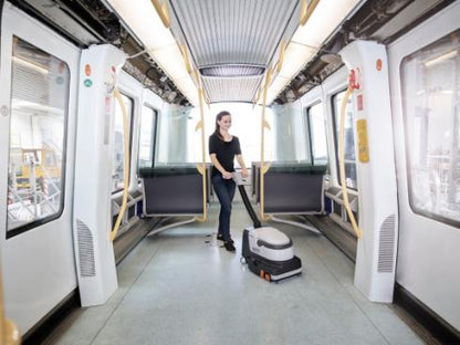 Person cleaning inside a modern train with a Nilfisk SC250 Scrubber cleaning machine.