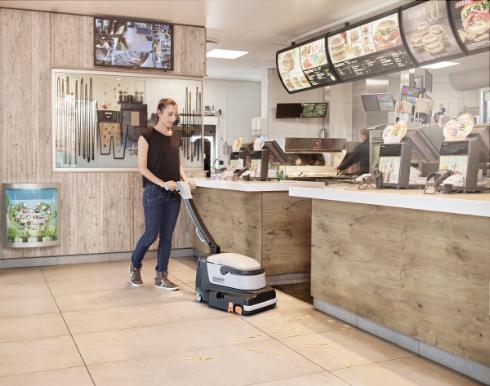 Person using a Nilfisk SC250 Scrubber in a fast-food restaurant.