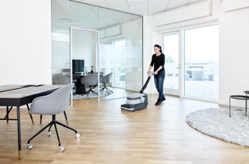 Person using a Nilfisk SC250 Scrubber in a modern office setting