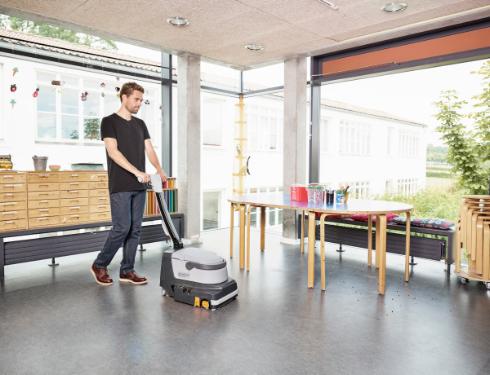 Person using a Nilfisk SC250 Scrubber floor cleaning machine in a educational setting