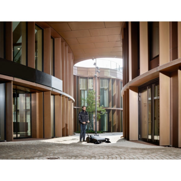 Modern architectural setting with a person standing in front of large glass doors.