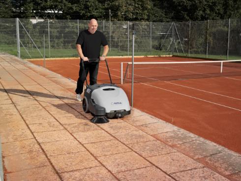 Person using a Nilfisk SW750 Walk-behind Sweeper on a tennis court
