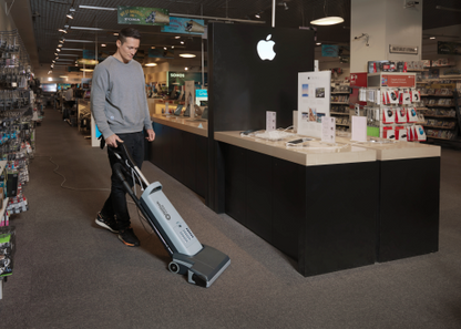 Person using a Nilfisk VU500 Upright Vacuum Cleaner in a retail store.