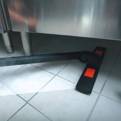 Black and red cleaning tool on a tiled floor with a metallic surface in the background