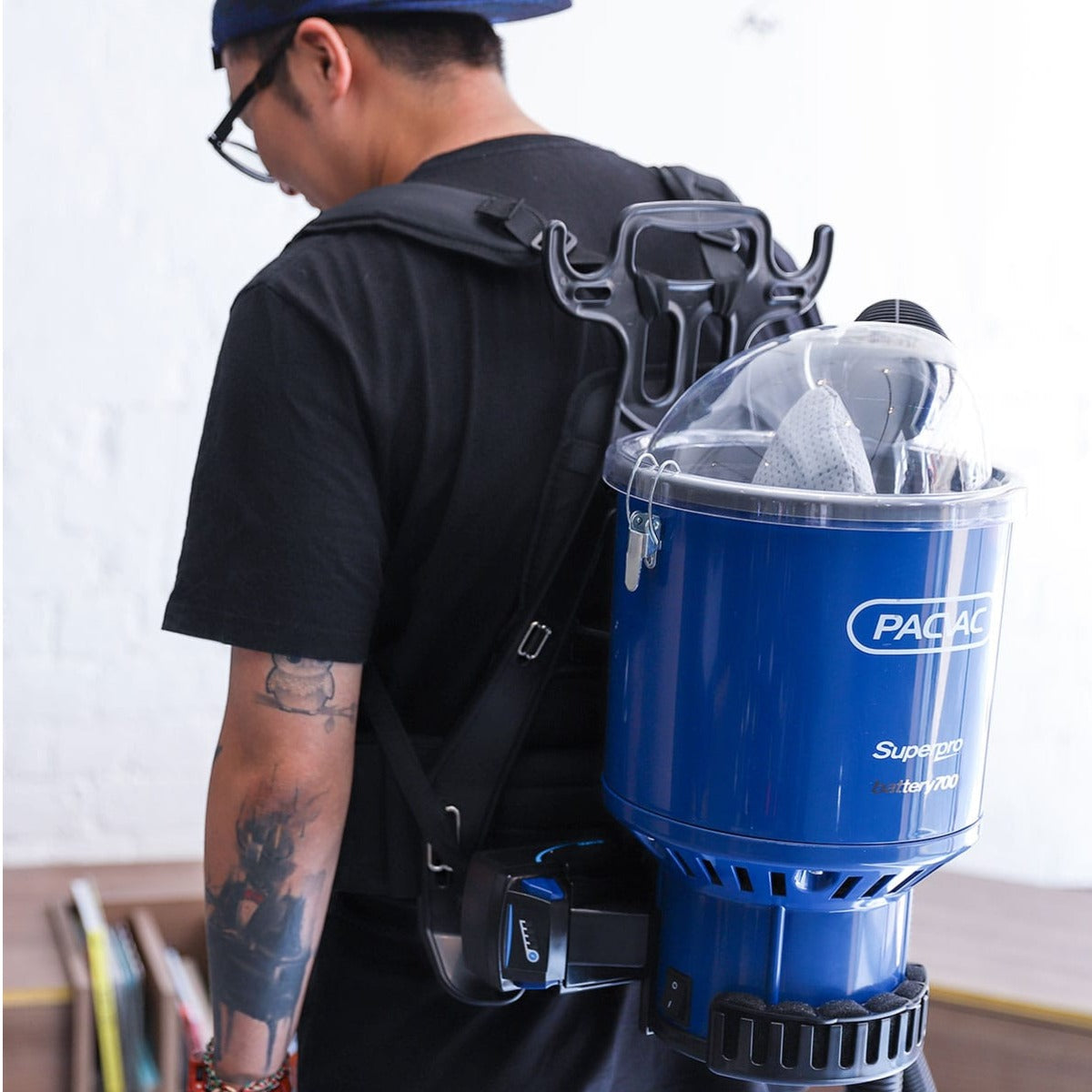 Person wearing a backpack with a blue Pacvac vacuum cleaner