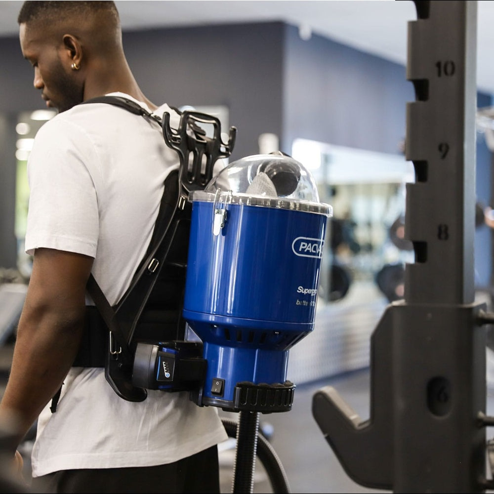 Person wearing a blue backpack with a visible brand logo in an indoor setting