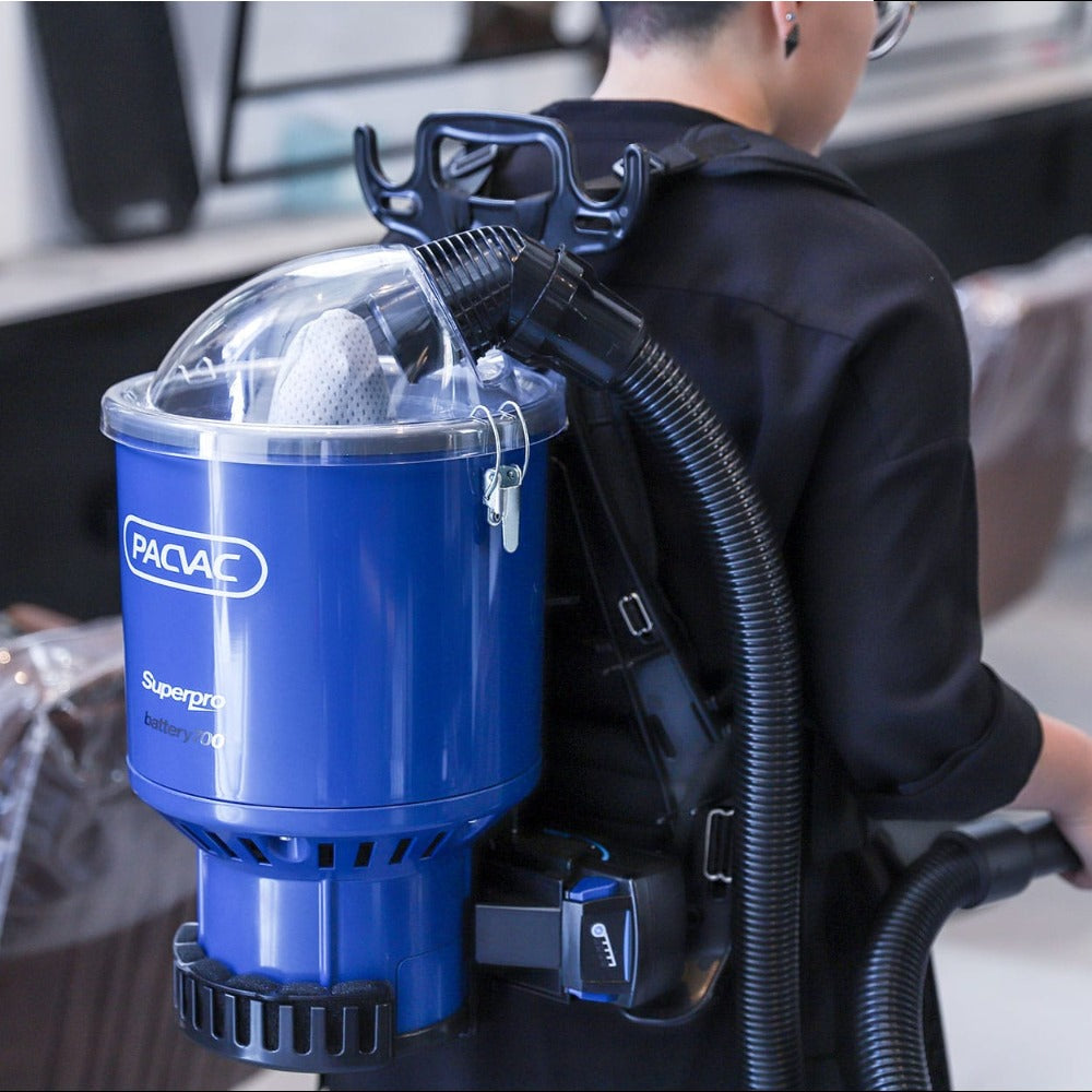 Person wearing a blue backpack vacuum cleaner with 'Pacvac' branding