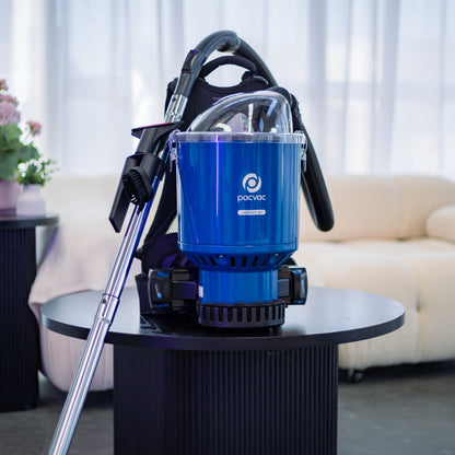 Blue Pacvac vacuum cleaner on a black table with a blurred indoor background